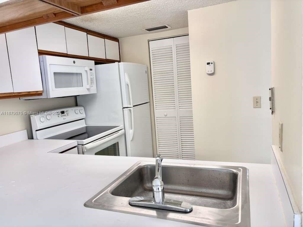 6340 La Costa Drive, Unit B Boca Raton, FL 33433 - Photo 5 of 16 a kitchen with a refrigerator a stove and a sink with wooden floor