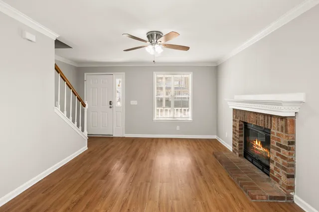 a view of an empty room with wooden floor fireplace and a window