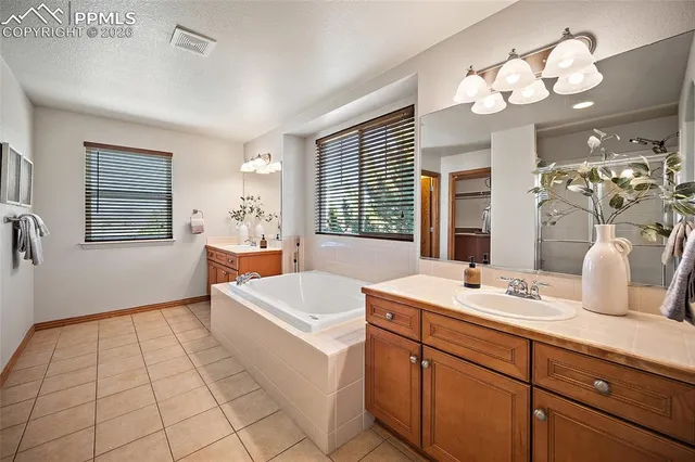 a spacious bathroom with a double vanity sink a mirror a bathtub and a window