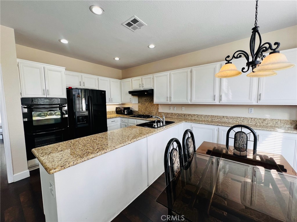 743 Orchard Loop Azusa, CA 91702 - Photo 12 of 38 a kitchen with granite countertop a refrigerator a stove a sink a center island and cabinets