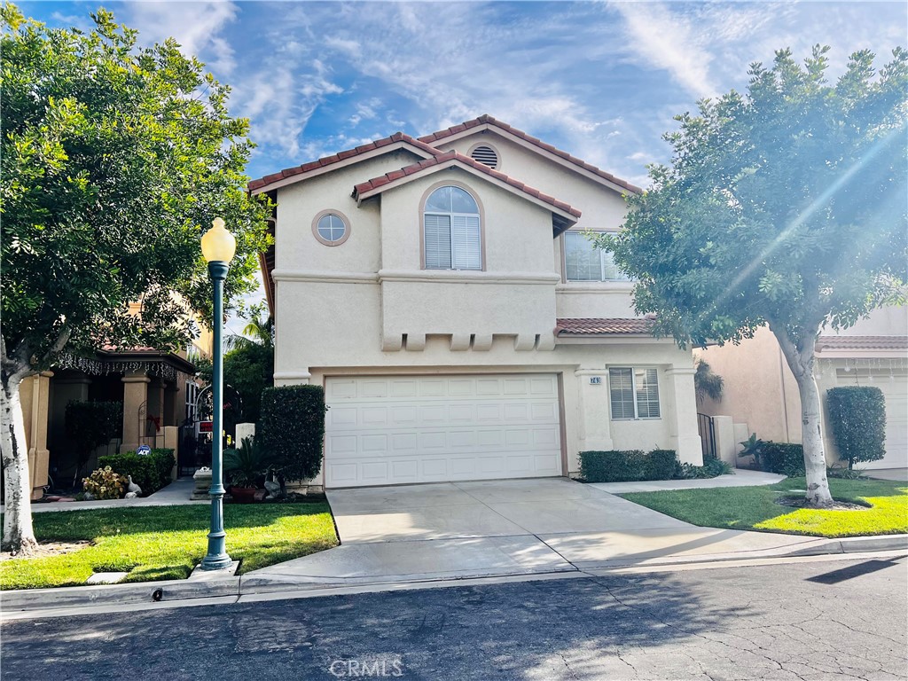 743 Orchard Loop Azusa, CA 91702 - Photo 2 of 38 a view of a white house with a swimming pool and a lawn chairs under an umbrella