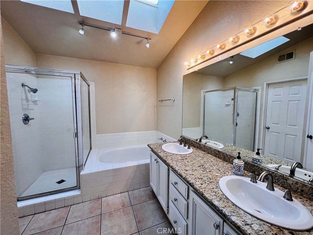 743 Orchard Loop Azusa, CA 91702 - Photo 27 of 38 a bathroom with a granite countertop sink a mirror a bathtub and shower