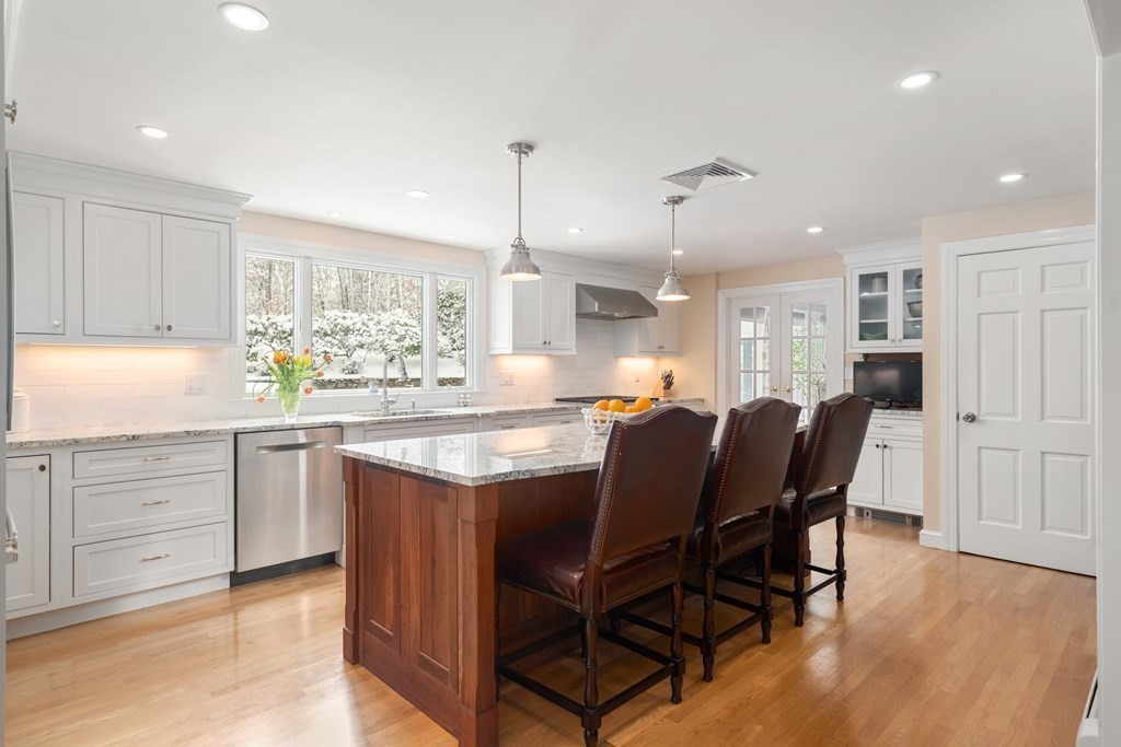 22 Hillcrest Road Weston, MA 02493 - Photo 6 of 31 a kitchen with kitchen island granite countertop wooden floors and white cabinets
