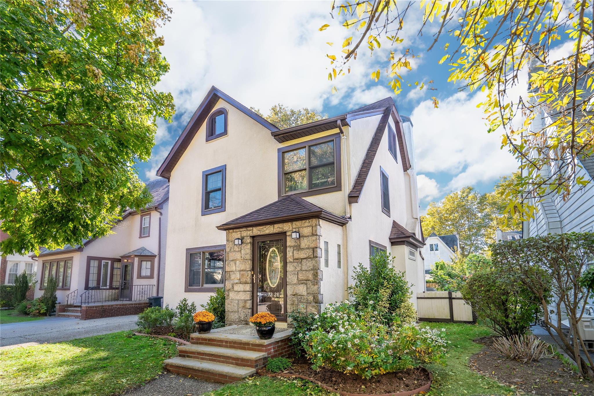 View of front facade featuring a shingled roof, fence, stone siding, and stucco siding
