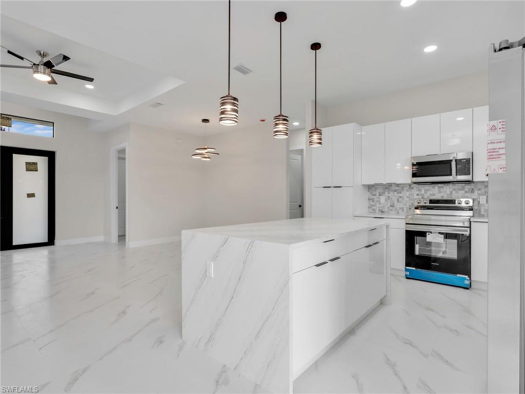 350 Delaware Road Lehigh Acres, FL 33936 - Photo 12 of 30 a large kitchen with granite countertop a stove a sink a refrigerator and a fireplace