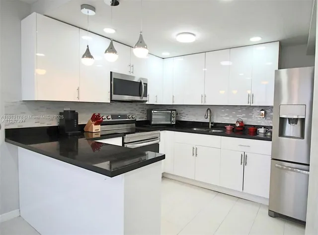 a kitchen with stainless steel appliances granite countertop a refrigerator a stove a sink a microwave and white cabinets