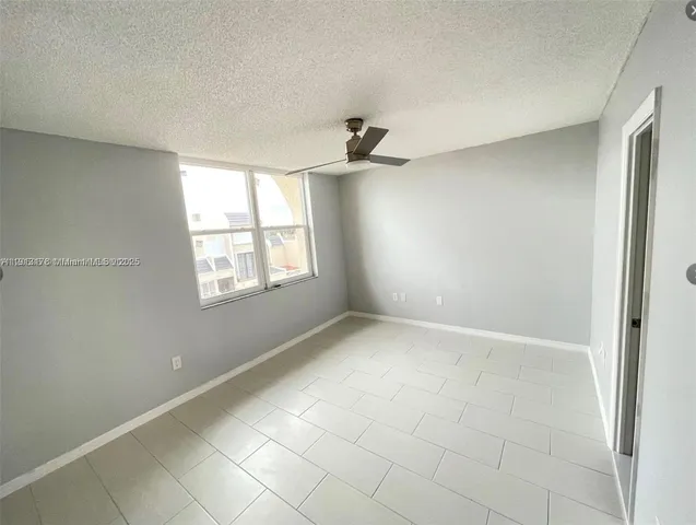 an empty room with windows and ceiling fan