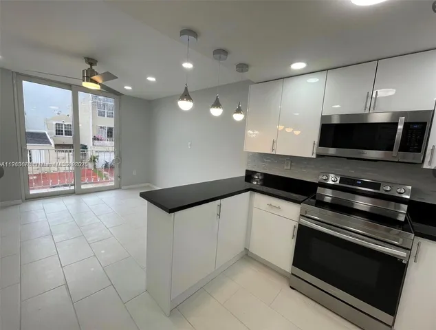 a kitchen with stainless steel appliances a stove a microwave and white cabinets