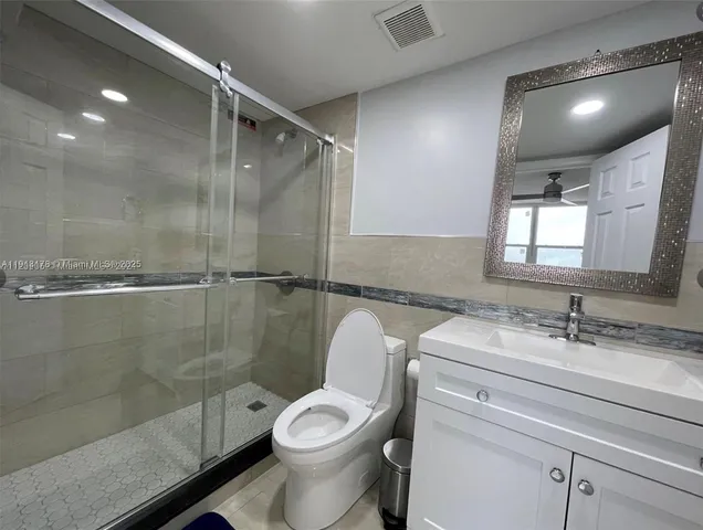 a bathroom with a granite countertop sink toilet and shower