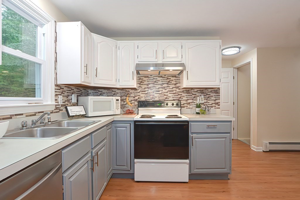 7 Proctor Road Pepperell, MA 01463 - Photo 5 of 40 a kitchen with stainless steel appliances granite countertop a sink stove and white cabinets with wooden floor