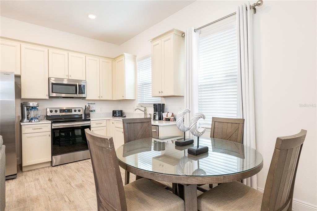 2956 Salted Rim Road Kissimmee, FL 34747 - Photo 5 of 12 a kitchen with stainless steel appliances a dining table chairs a stove a microwave and a refrigerator