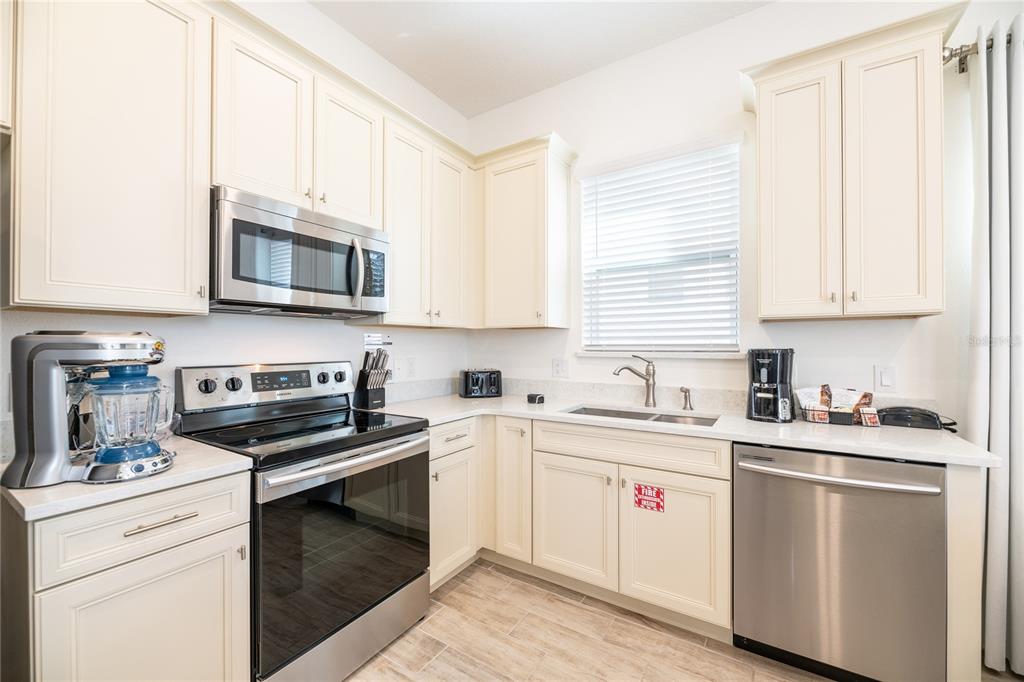 2956 Salted Rim Road Kissimmee, FL 34747 - Photo 6 of 12 a kitchen with stainless steel appliances granite countertop white cabinets a sink a stove a microwave and wooden cabinets