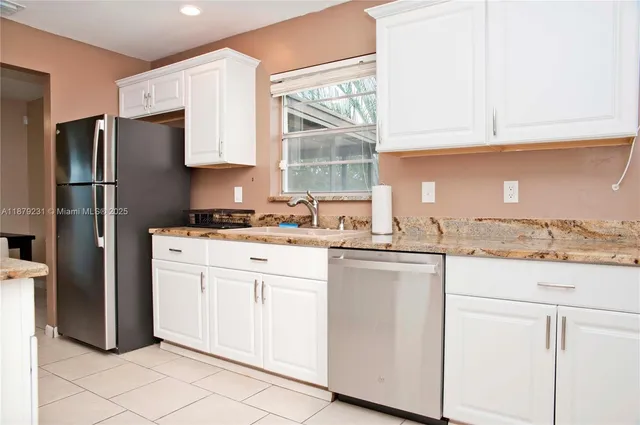 a kitchen with granite countertop white cabinets white stainless steel appliances a sink and a window