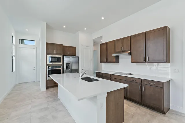 a kitchen with stainless steel appliances kitchen island granite countertop a sink and a refrigerator