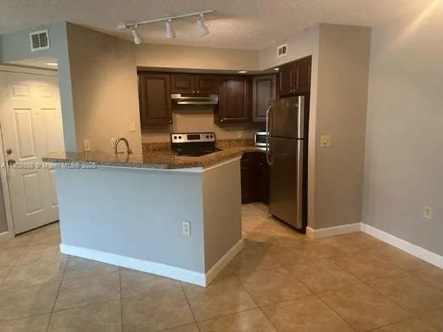 a kitchen with kitchen island granite countertop cabinets and refrigerator