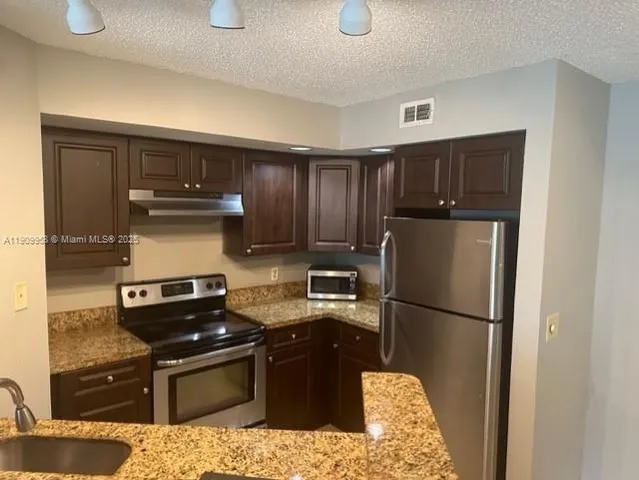 a kitchen with granite countertop stainless steel appliances and wooden cabinets