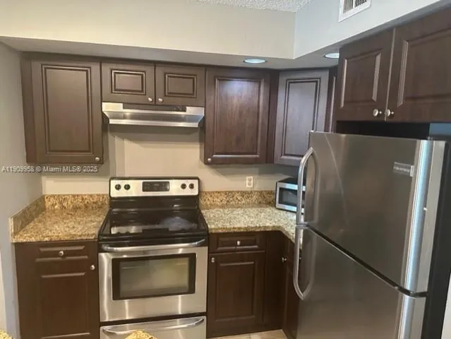 a kitchen with stainless steel appliances granite countertop a refrigerator stove and sink