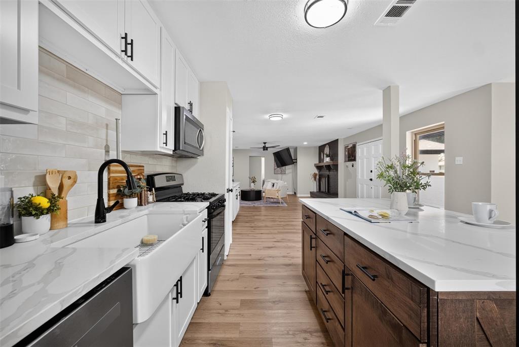 3919 Ridgeoak Way Farmers Branch, TX 75244 - Photo 5 of 28 Kitchen featuring white shaker cabinetry, white farmhouse sink, black hardware and fixtures, and light wood-finish flooring