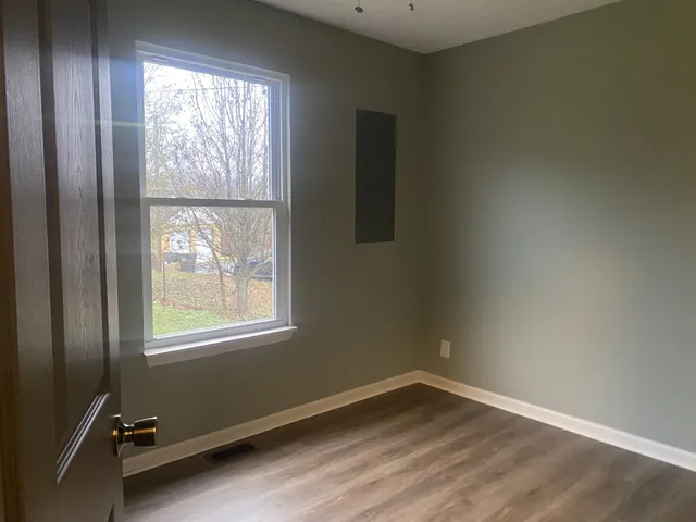 an empty room with wooden floor windows and fan