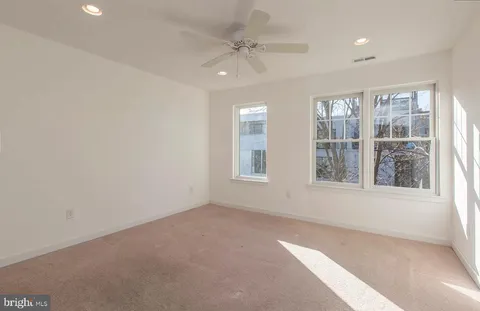 an empty room with chandelier fan and windows