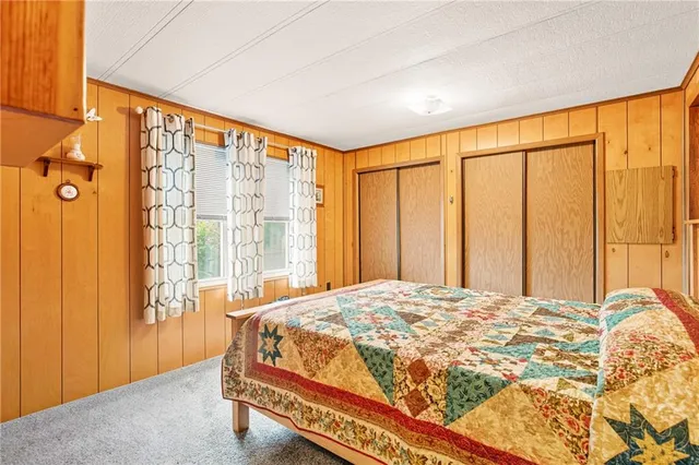 a bed sitting in a spacious bedroom next to a cabinet and a window
