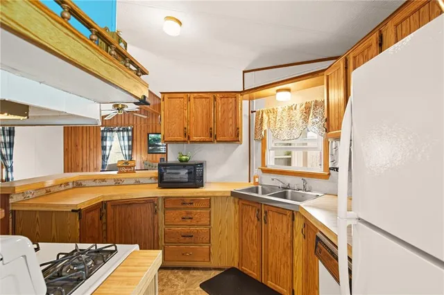 a kitchen with a sink appliances cabinets and a large window
