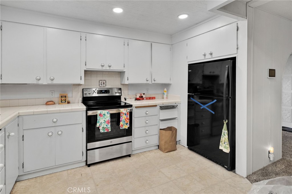 2494 Main Street Barstow, CA 92311 - Photo 15 of 36 a kitchen with a refrigerator and white cabinets