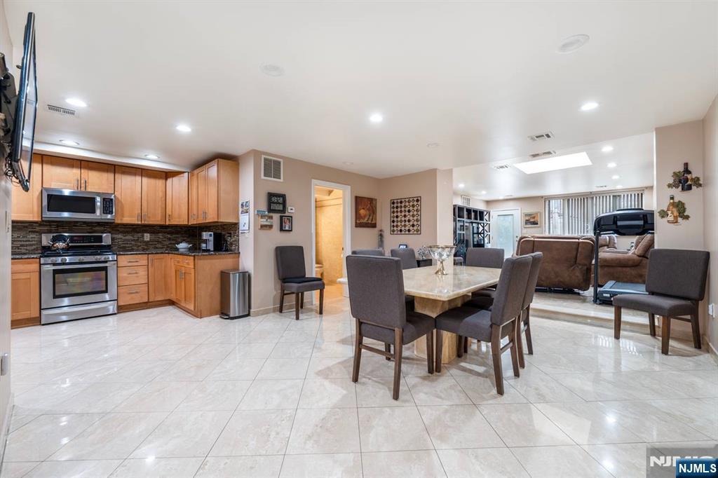 413 Adams Street Hoboken, NJ 07030 - Photo 21 of 40 a kitchen with stainless steel appliances kitchen island granite countertop a table and chairs in it