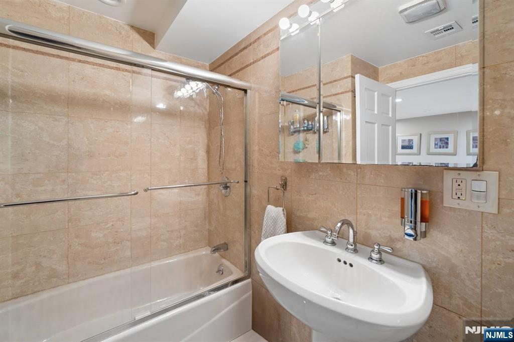 413 Adams Street Hoboken, NJ 07030 - Photo 29 of 40 a white bath tub sitting next to a white sink and a mirror