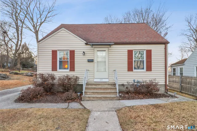 a view of a white house with a yard and large tree