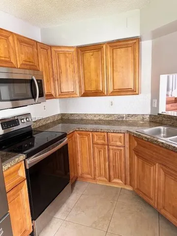 a kitchen with stainless steel appliances granite countertop a stove a sink and a microwave