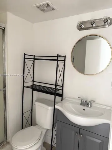 a bathroom with a toilet sink mirror and vanity