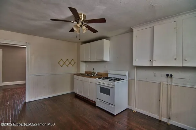 a kitchen with cabinets wooden floor and stainless steel appliances