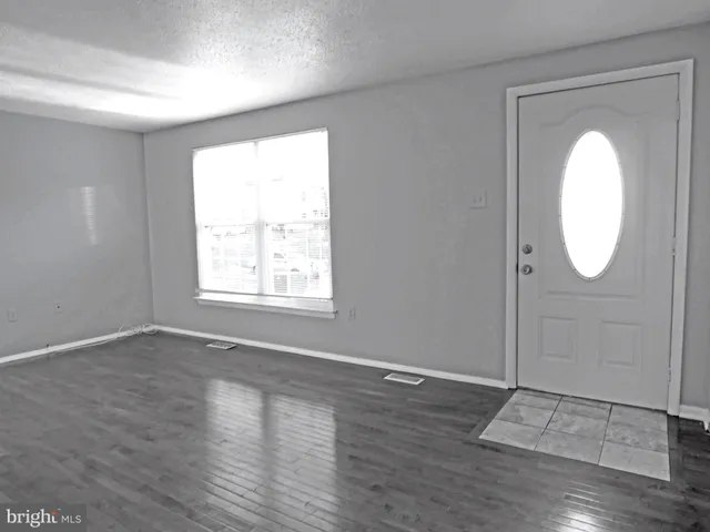 an empty room with wooden floor mirror and windows
