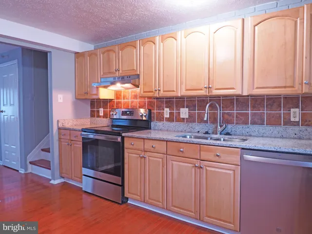 a kitchen with stainless steel appliances granite countertop a stove a sink and a white cabinets