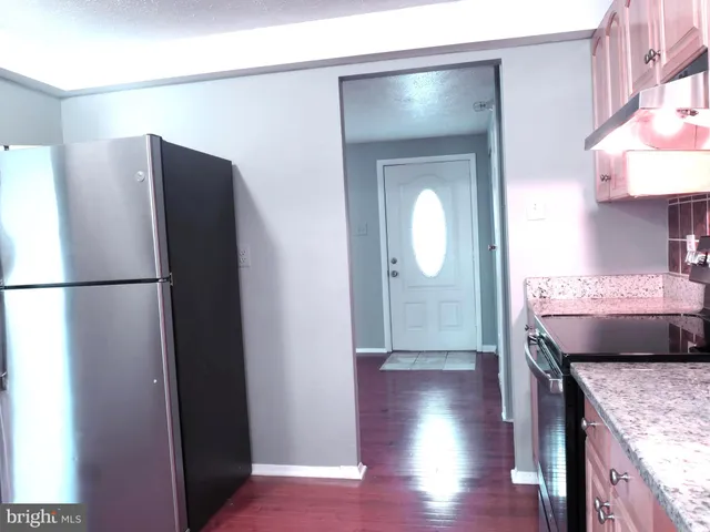 a kitchen with a refrigerator and a wooden floor