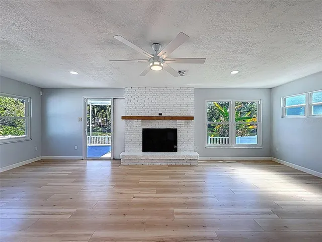 an empty room with windows fireplace and a ceiling fan