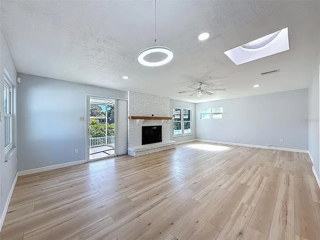 an empty room with wooden floor fireplace and windows