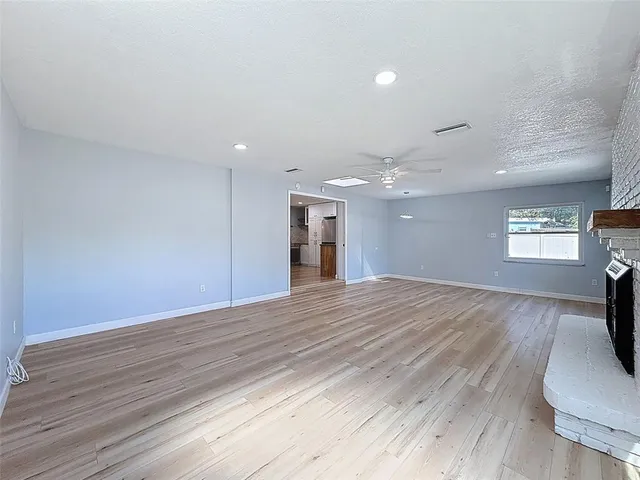 a view of empty room with wooden floor and fireplace