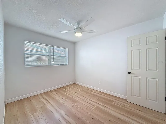 a view of empty room with wooden floor and ceiling fan