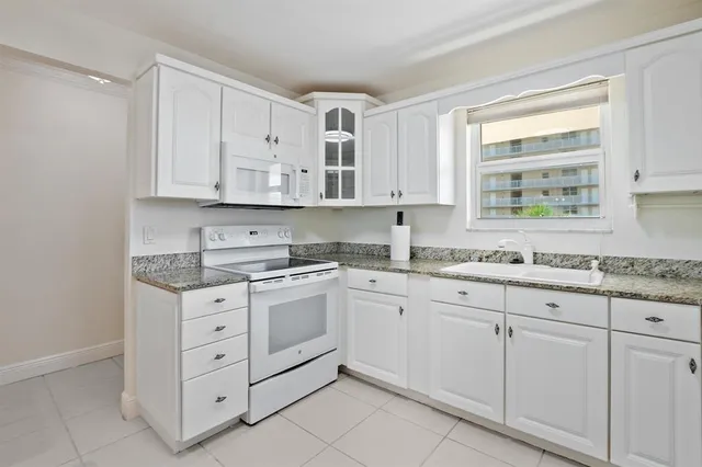 a kitchen with granite countertop white cabinets and sink