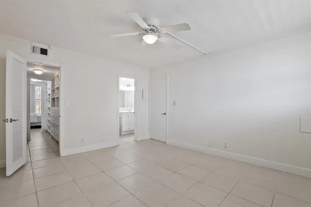 an empty room with closet and a ceiling fan