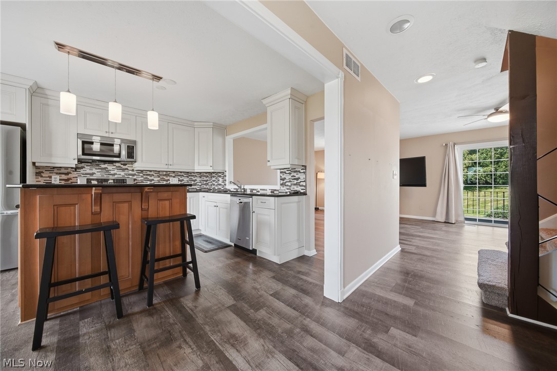 824 South Chillicothe Road, Unit 2 Aurora, OH 44202 - Photo 14 of 42 Modern kitchen featuring white cabinetry, black countertops, and a mosaic tile backsplash
