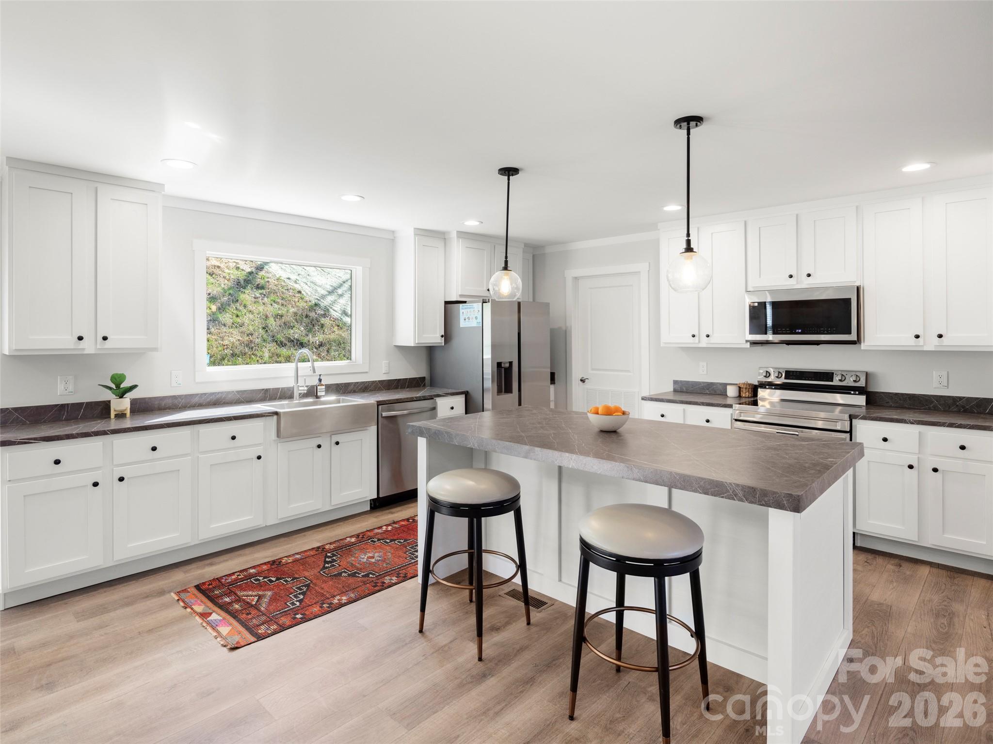 a kitchen with stainless steel appliances kitchen island granite countertop a stove a sink and a refrigerator