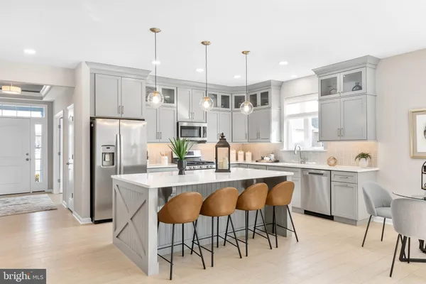 a large kitchen with cabinets chairs and refrigerator
