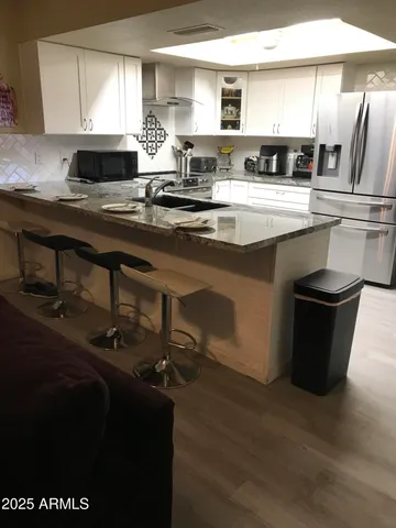 a kitchen with stainless steel appliances granite countertop a sink wooden cabinets and wooden floor