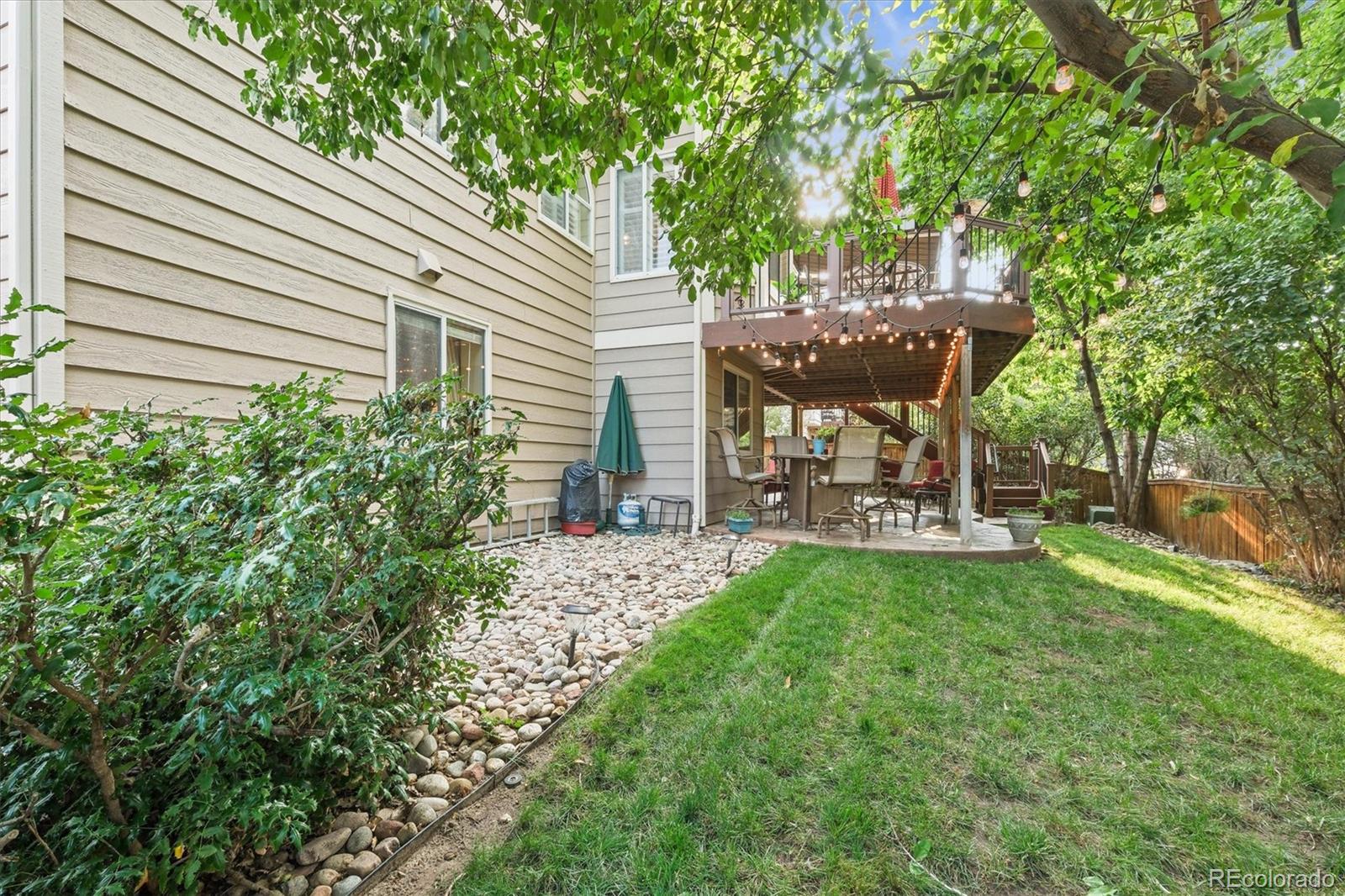 3115 White Oak Lane Highlands Ranch, CO 80129 - Photo 39 of 43 a view of a backyard with table and chairs and potted plants and large trees