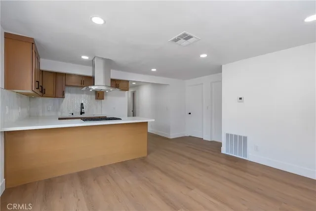 a large kitchen with stainless steel appliances a large counter top a wooden floor and a sink