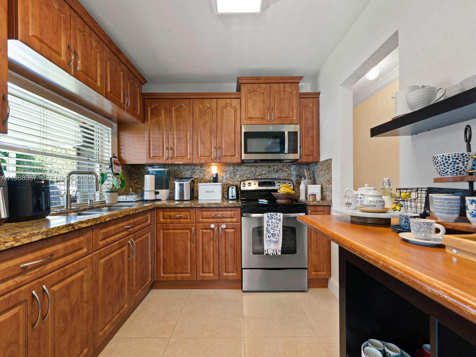 8530 Northwest 179th Street Hialeah, FL 33015 - Photo 18 of 28 a kitchen with stainless steel appliances kitchen island granite countertop a sink counter space cabinets and a window