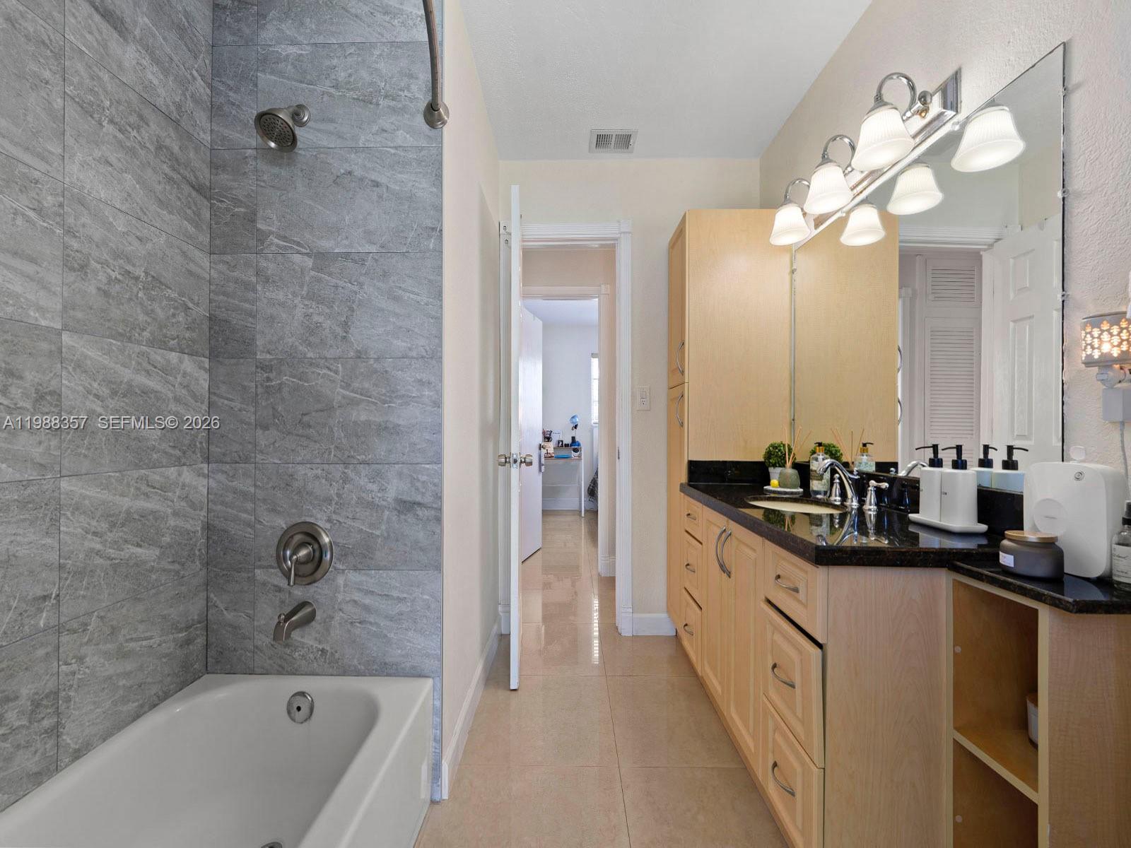 8530 Northwest 179th Street Hialeah, FL 33015 - Photo 23 of 28 a bathroom with a double vanity sink a mirror a bathtub and a shower